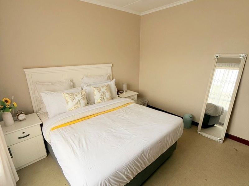 A well-lit bedroom featuring neutral wall tones, carpeted flooring, and a simple ceiling light fixture.