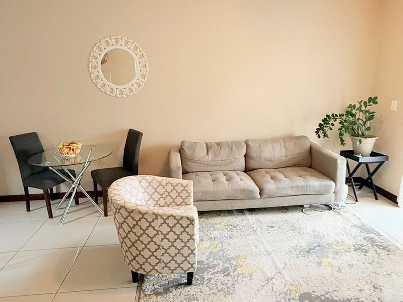 A bright living area featuring neutral wall tones and large format floor tiles, providing a clean and functional space for relaxation.