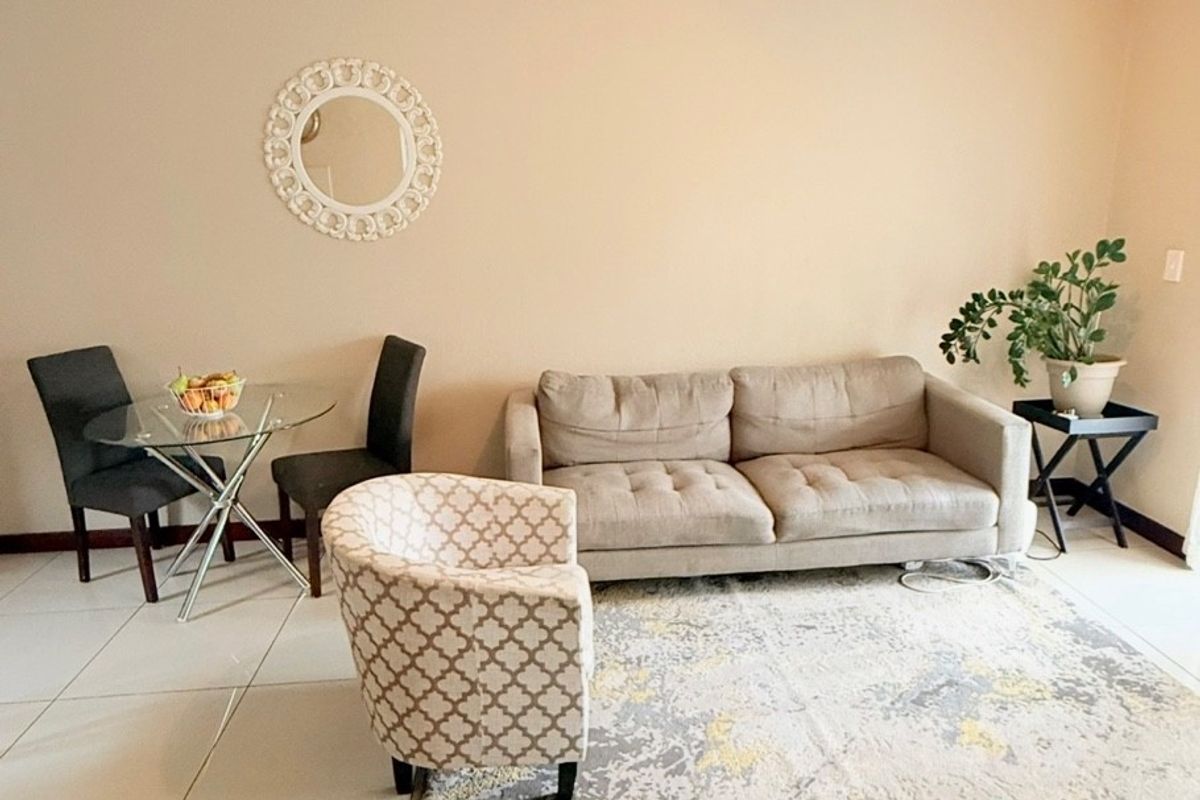 A bright living area featuring neutral wall tones and large format floor tiles, providing a clean and functional space for relaxation.