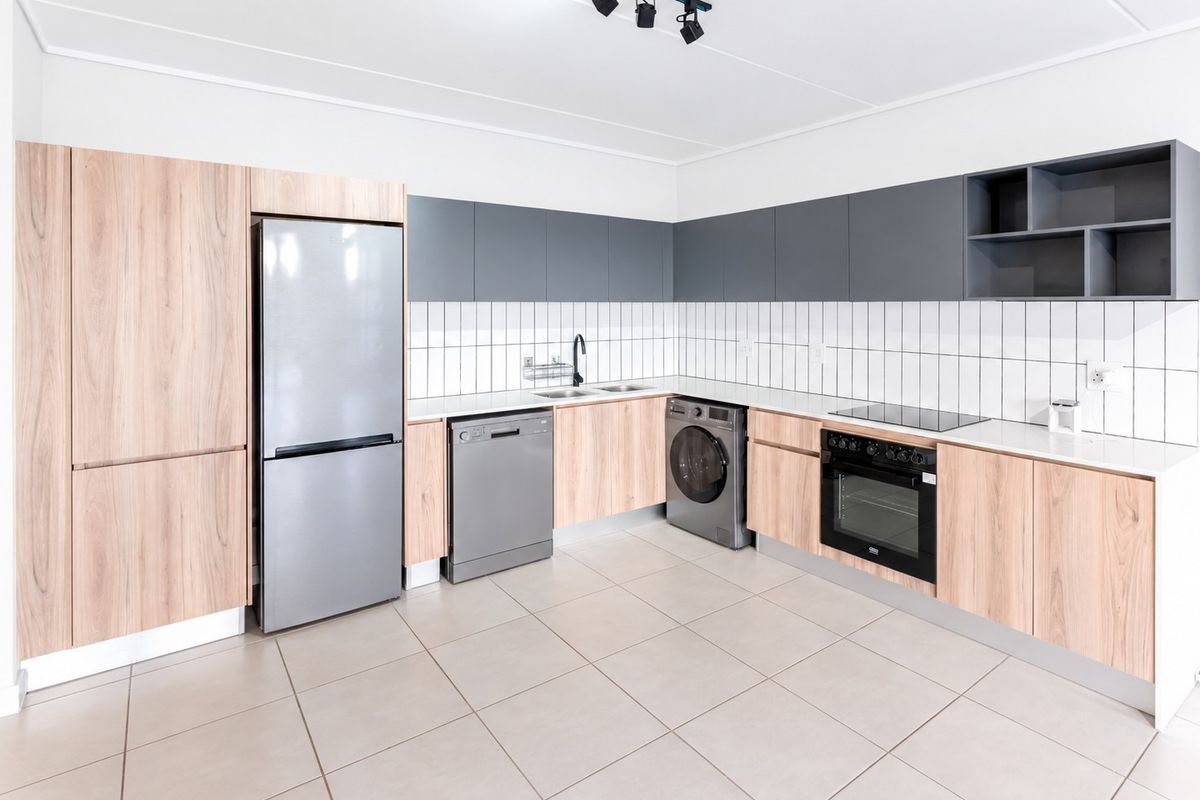Modern kitchen featuring light wood and grey cabinetry, tiled backsplash, integrated oven, electric hob, and tiled flooring in a clean, contemporary layout.