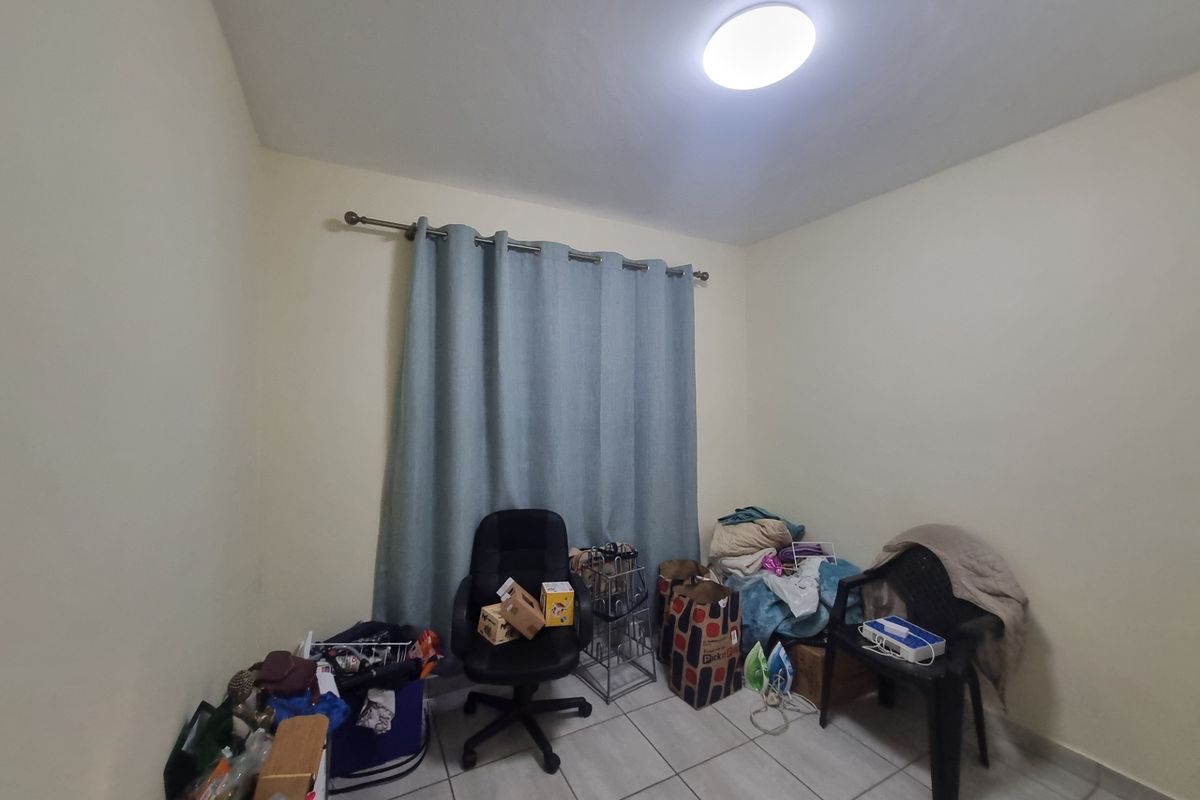 A functional bedroom space featuring tiled flooring and a curtain rod, offering a blank canvas for personalization.