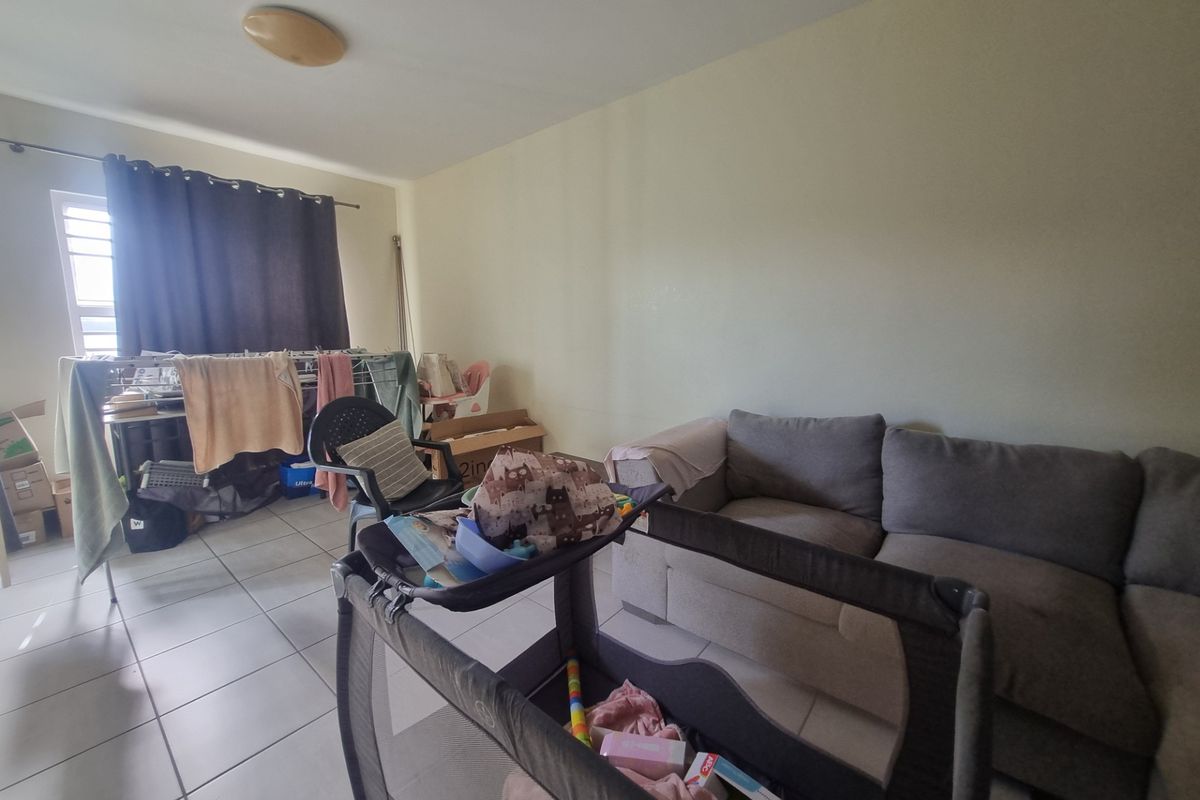 A living room area featuring tiled flooring and a window with a curtain rod, providing a functional space for daily living.