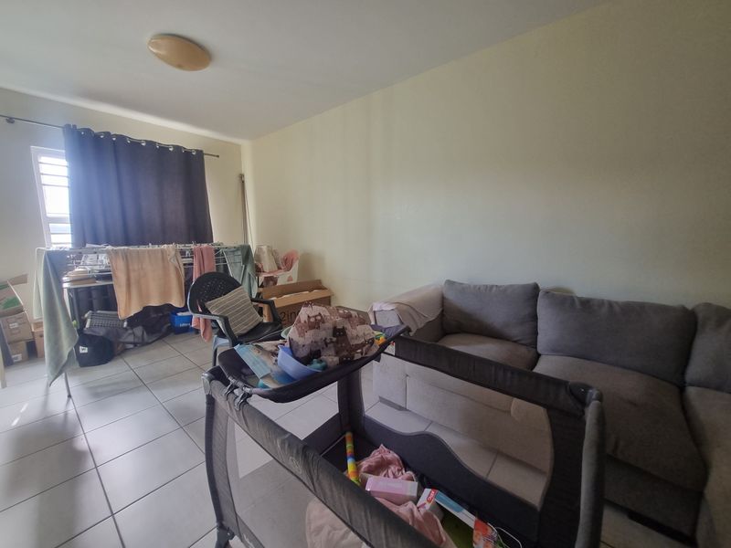 A living room area featuring tiled flooring and a window with a curtain rod, providing a functional space for daily living.