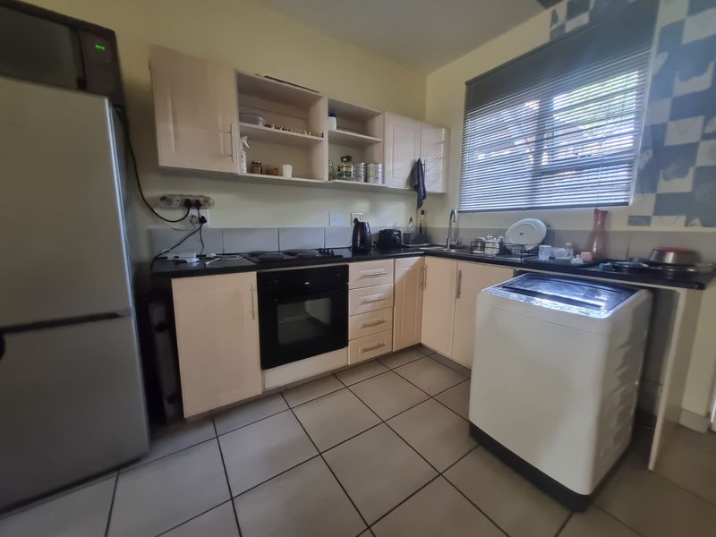 Functional kitchen featuring built-in cabinetry, integrated oven and hob, tiled flooring, and a stainless steel sink with a window view.