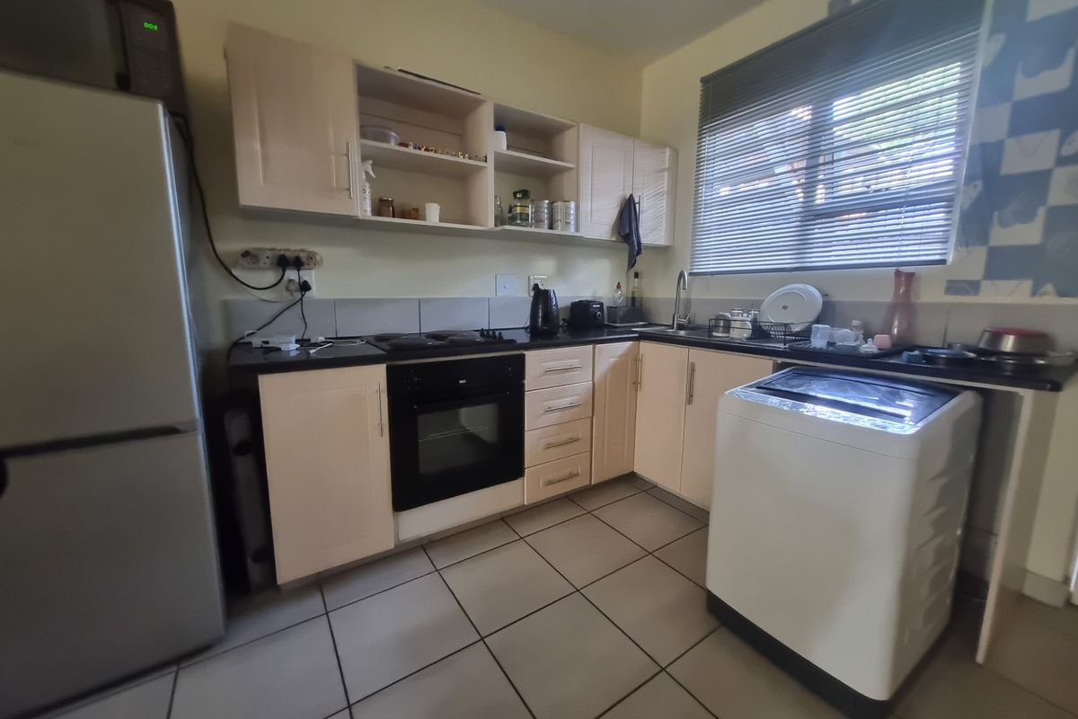 Functional kitchen featuring built-in cabinetry, integrated oven and hob, tiled flooring, and a stainless steel sink with a window view.