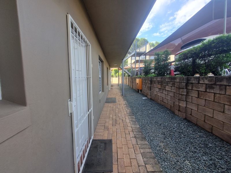 A side exterior walkway featuring brick paving, a security gate, and a concrete block retaining wall along the property boundary.