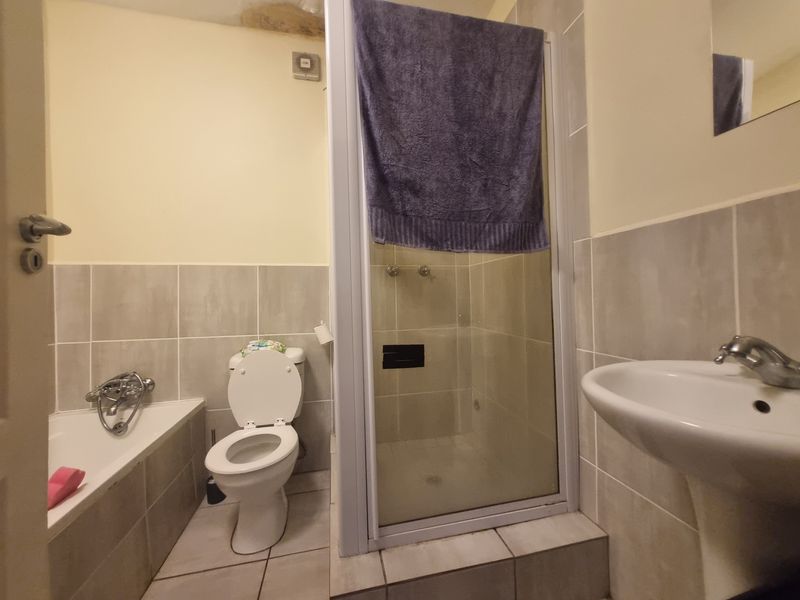 Bathroom featuring a bathtub, separate shower enclosure, pedestal basin, and toilet, with tiled finishes and visible ceiling water damage.