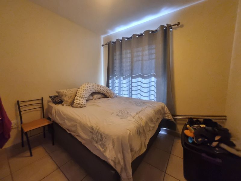 A standard bedroom featuring tiled flooring and a window with a fitted curtain rod.