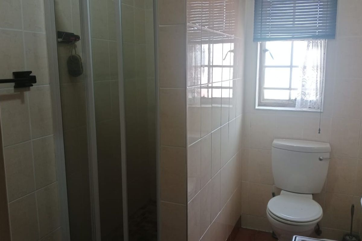 A functional bathroom featuring a shower enclosure, toilet, and tiled wall finishes, providing a practical layout for daily use.