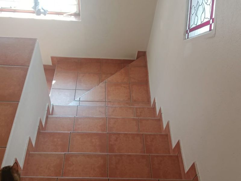 A staircase featuring terracotta-style floor tiles and a decorative stained glass window, providing a functional transition between levels.