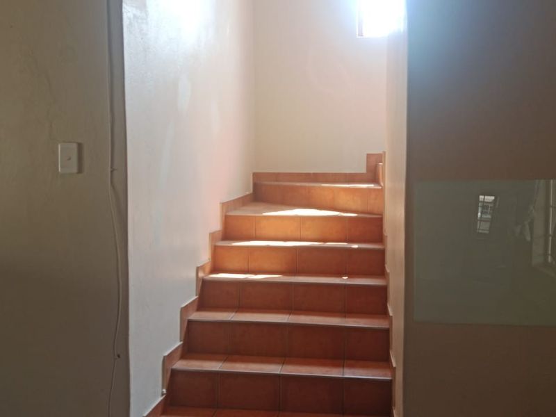 A staircase featuring tiled steps and a glass wall panel, requiring minor cosmetic repairs to the surrounding walls.