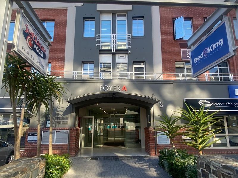Front entrance facade of a commercial office building featuring brick and painted finishes, glass doors, and prominent business signage.