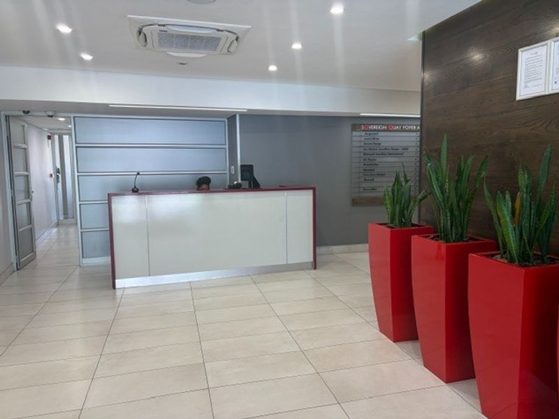 A professional office building foyer featuring a reception desk, tiled flooring, recessed lighting, and a directory board for tenants.