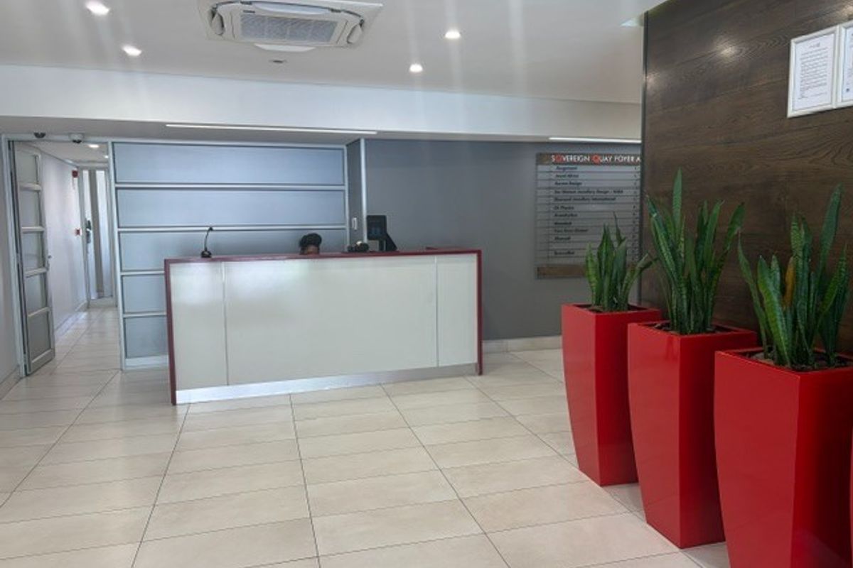 A professional office building foyer featuring a reception desk, tiled flooring, recessed lighting, and a directory board for tenants.