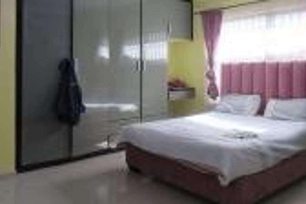 A bedroom featuring built-in cupboards and tiled flooring, offering a functional space with natural light.