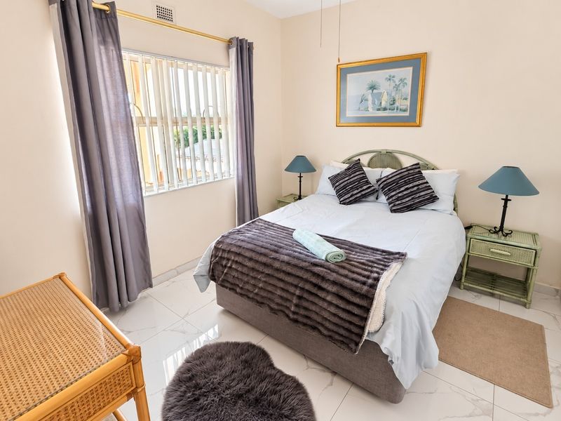 A well-lit bedroom featuring tiled flooring, a built-in wardrobe, and vertical blinds, offering a functional and comfortable living space.