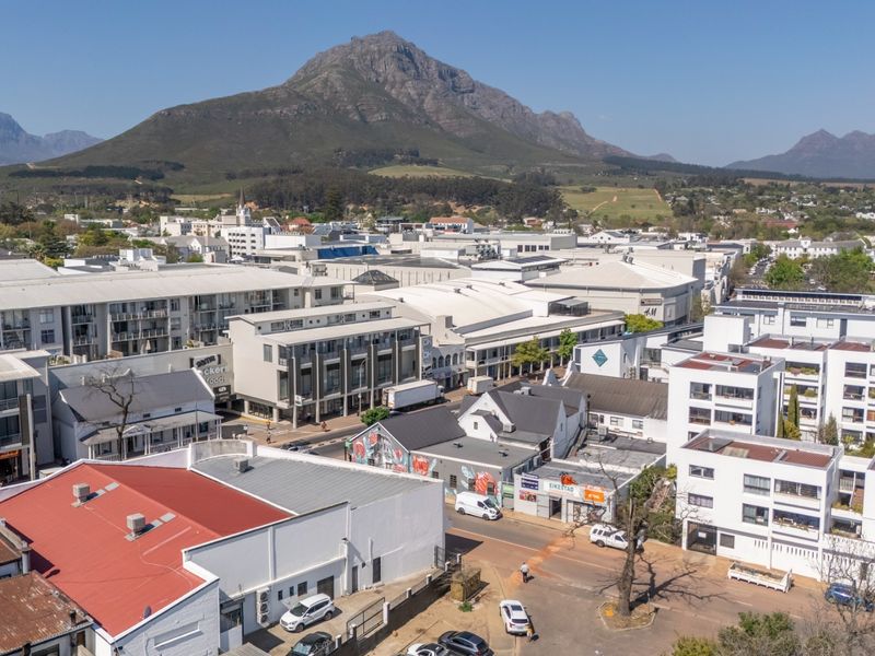 An aerial view of the surrounding urban neighborhood and commercial district, showcasing the property's location in relation to the town and mountain landscape.