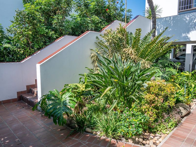 A well-maintained outdoor area featuring a tiled staircase leading to an upper level, complemented by a lush, established garden and paved patio space.