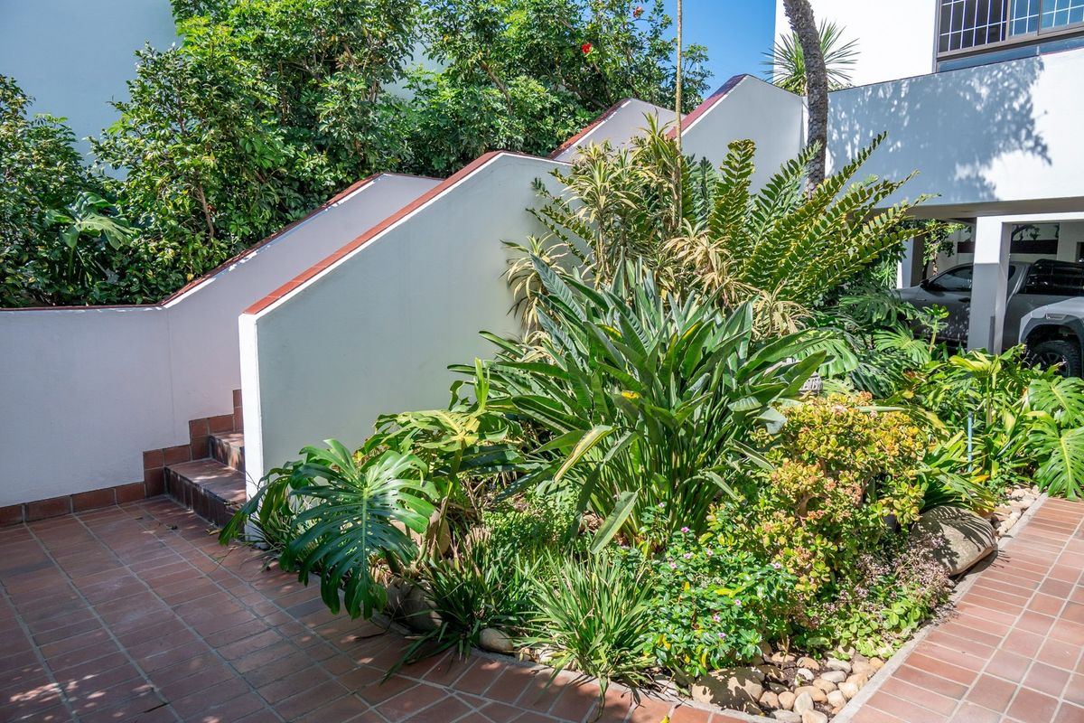A well-maintained outdoor area featuring a tiled staircase leading to an upper level, complemented by a lush, established garden and paved patio space.