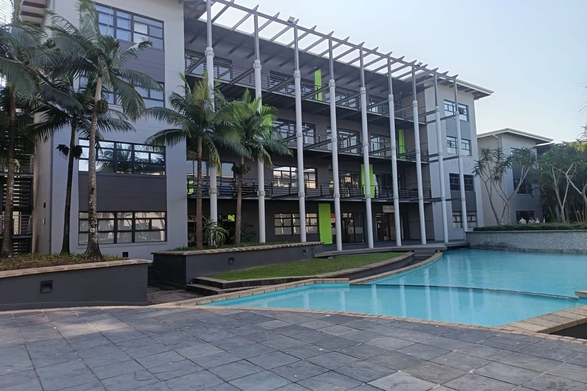 Modern multi-story office building exterior featuring a swimming pool, paved terrace area, and integrated balcony structures with contemporary architectural design.