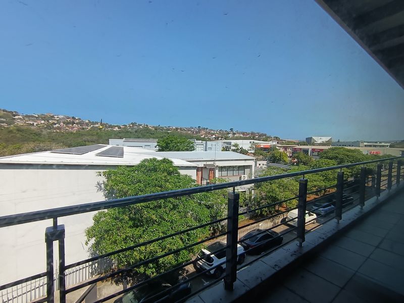 A balcony with metal railings overlooking the surrounding office park and neighborhood landscape.