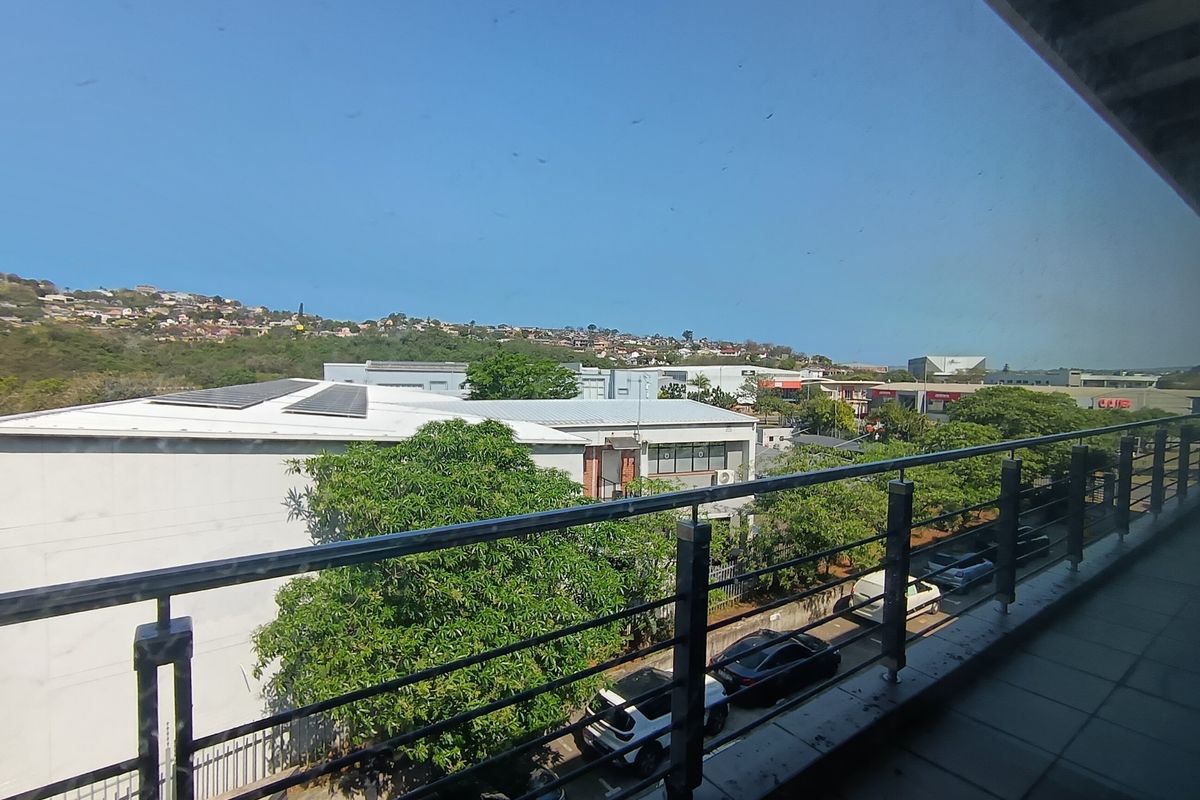 A balcony with metal railings overlooking the surrounding office park and neighborhood landscape.