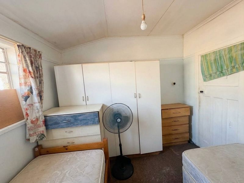 A bedroom featuring a built-in wardrobe, requiring cosmetic updates to the ceiling, walls, and flooring to improve its overall condition.