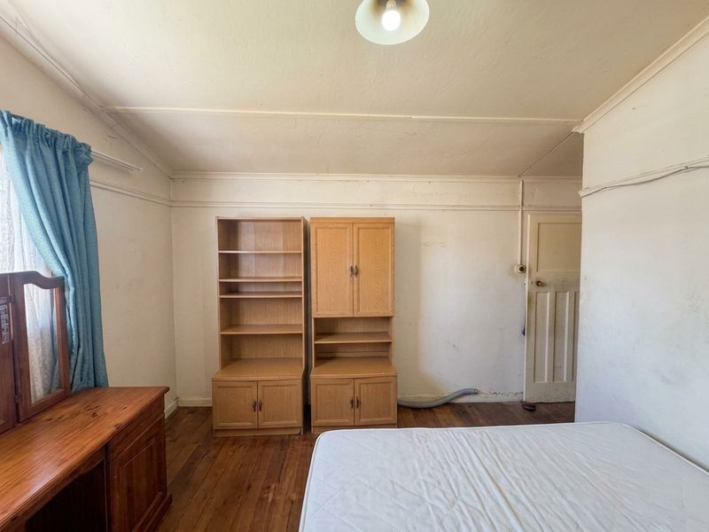 A bedroom featuring original timber flooring, coved ceilings, and picture rails, currently requiring cosmetic refurbishment and wall repairs.