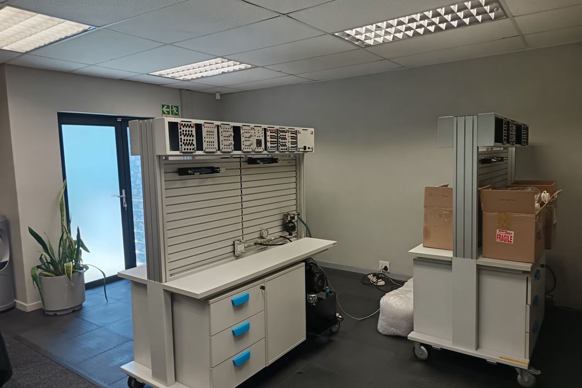 A functional office space featuring a suspended ceiling with recessed lighting, a glass panel door, and modular workstations.