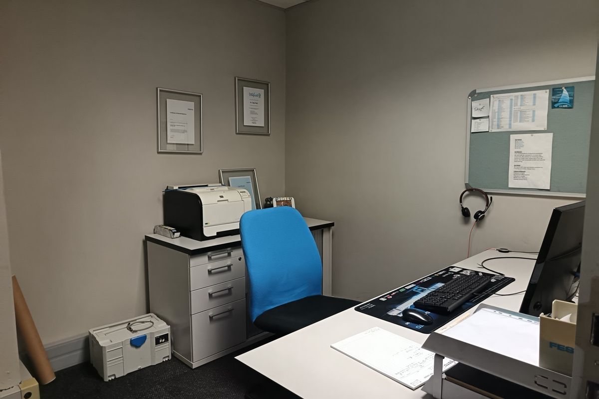 A functional office space featuring neutral wall finishes, carpeted flooring, and a suspended ceiling, suitable for professional use.