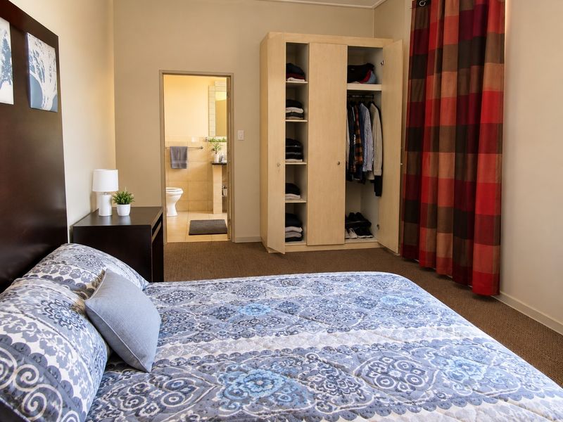 A carpeted bedroom featuring a built-in wardrobe and direct access to an en-suite bathroom.
