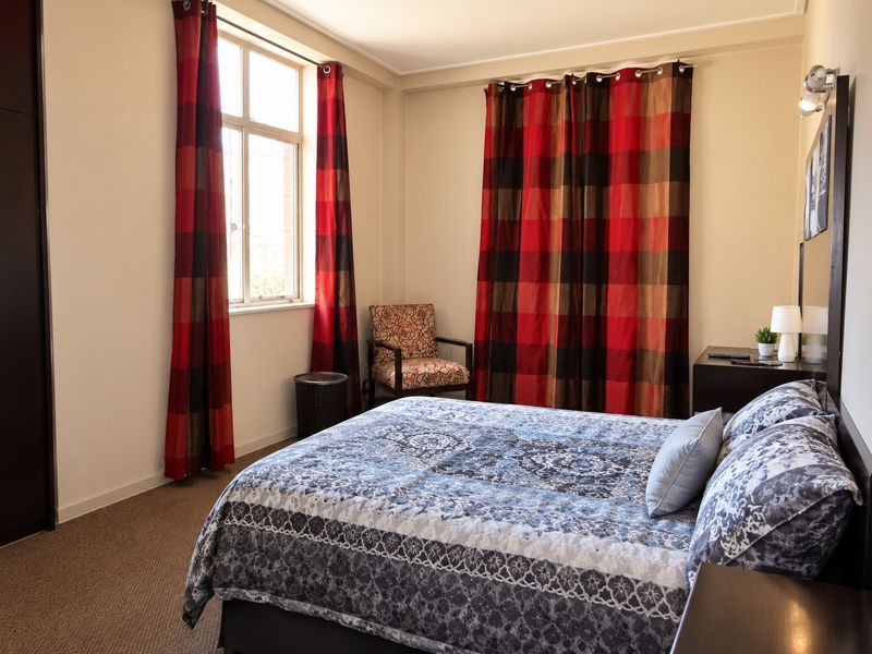 A bedroom featuring carpet flooring, a built-in wardrobe, and a window with natural light.