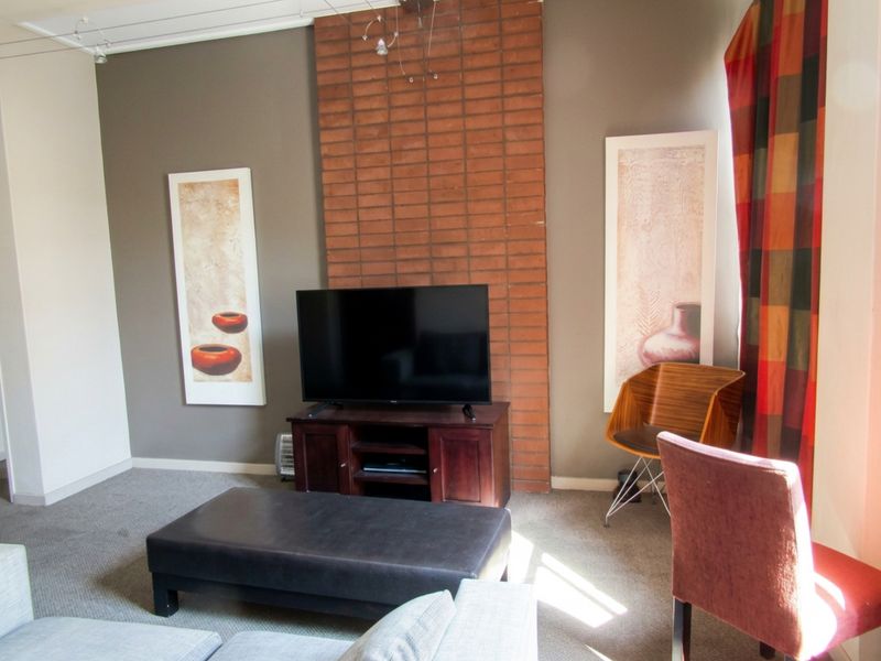 A living room featuring a prominent exposed brick chimney breast and neutral wall tones, providing a cozy and functional space.