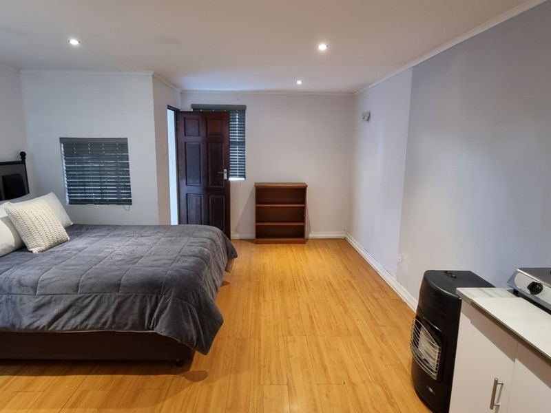 Open-plan studio space featuring bamboo flooring, recessed lighting, and a compact kitchenette area with a gas hob.