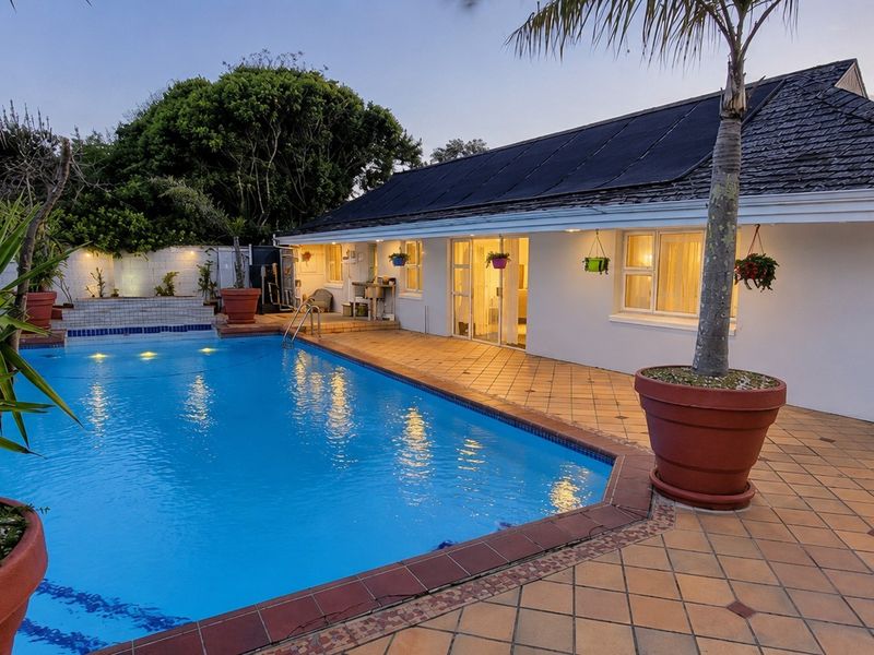 A well-maintained outdoor pool area featuring a tiled patio, swimming pool, and shingle roof, perfect for outdoor relaxation and entertainment.