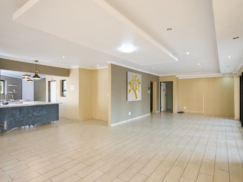 Spacious open-plan living area featuring modern tiled flooring, recessed ceiling lighting, and a functional kitchen island with built-in cabinetry.