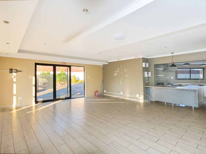 Spacious open-plan living area featuring tiled flooring, recessed lighting, and an integrated kitchen with a central island and modern cabinetry.
