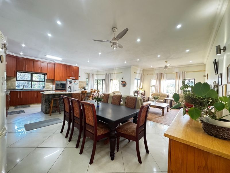 Spacious open-plan living, dining, and kitchen area featuring tiled floors, recessed lighting, and a well-appointed kitchen with built-in cabinetry and stone countertops.