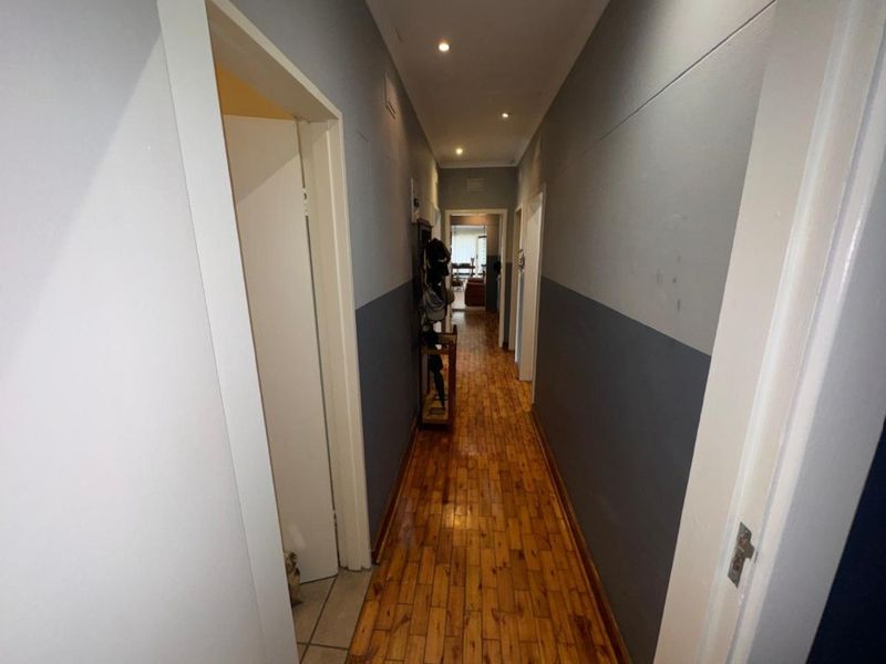 A functional hallway featuring timber flooring and recessed downlighting, providing access to multiple rooms within the home.