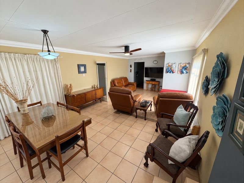 Spacious open-plan living and dining area featuring neutral tiled flooring, coved cornicing, and a central ceiling fan, offering a versatile layout for family living.