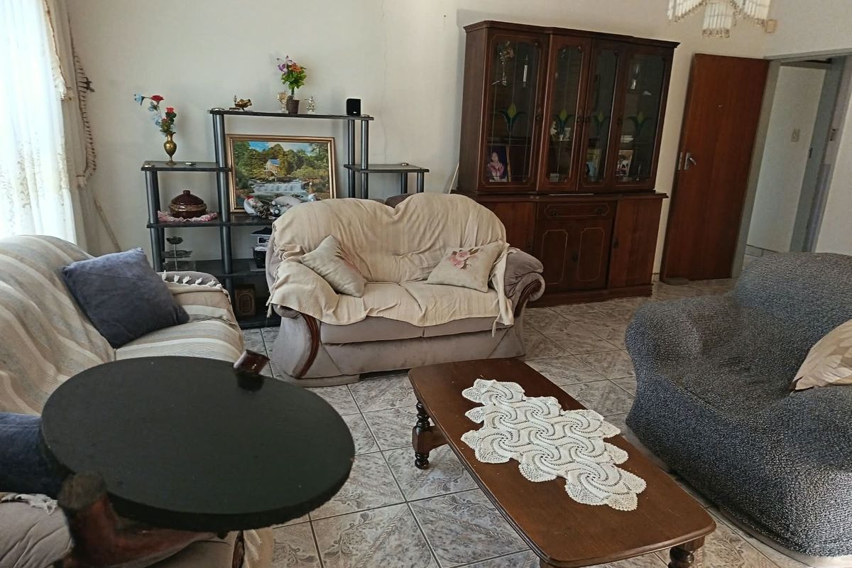 A living room featuring tiled flooring and a ceiling light fixture, showing signs of wear including a visible wall crack.