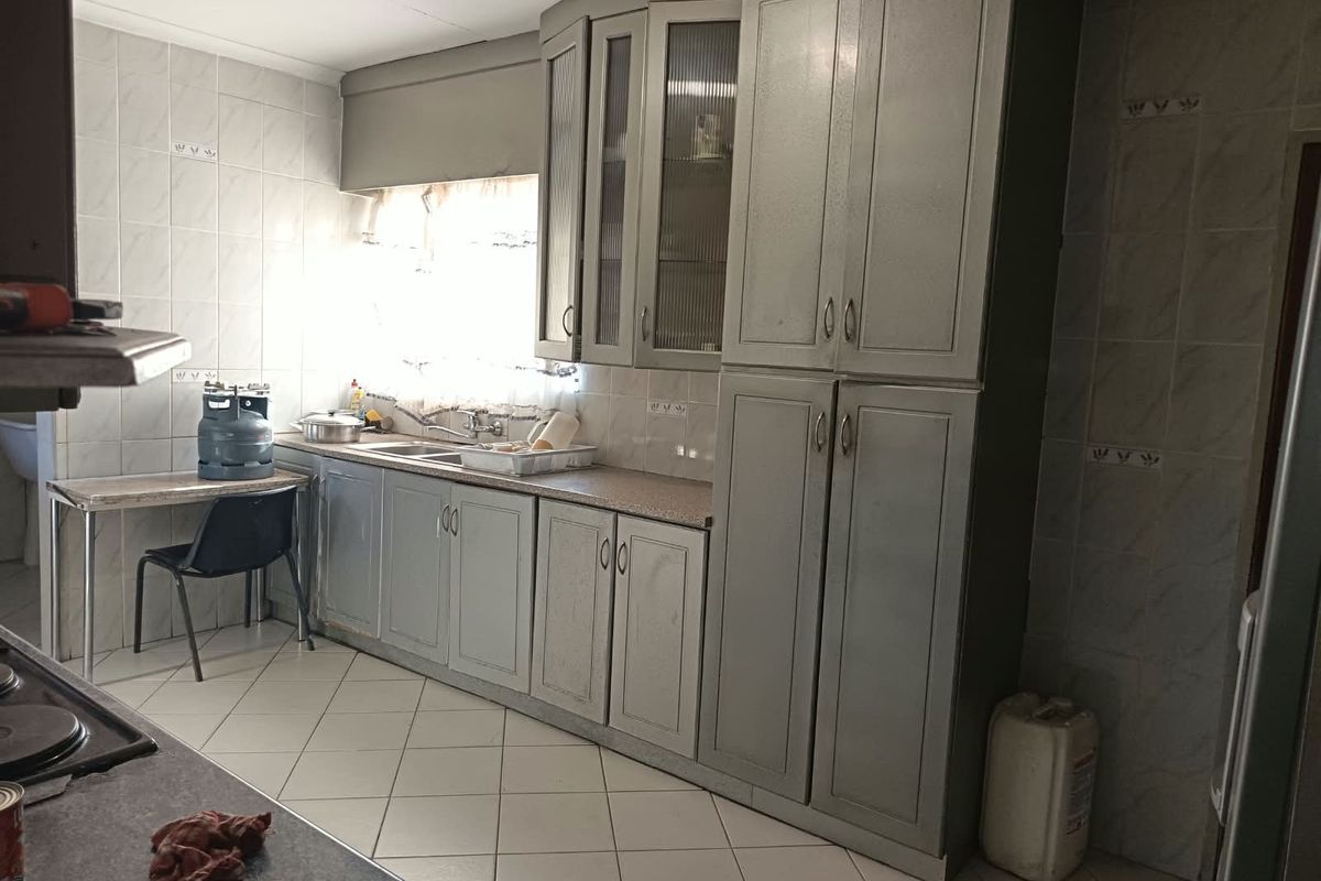 A functional kitchen featuring built-in cabinetry, tiled walls, and tiled flooring, offering a dated aesthetic that could benefit from modern updates.