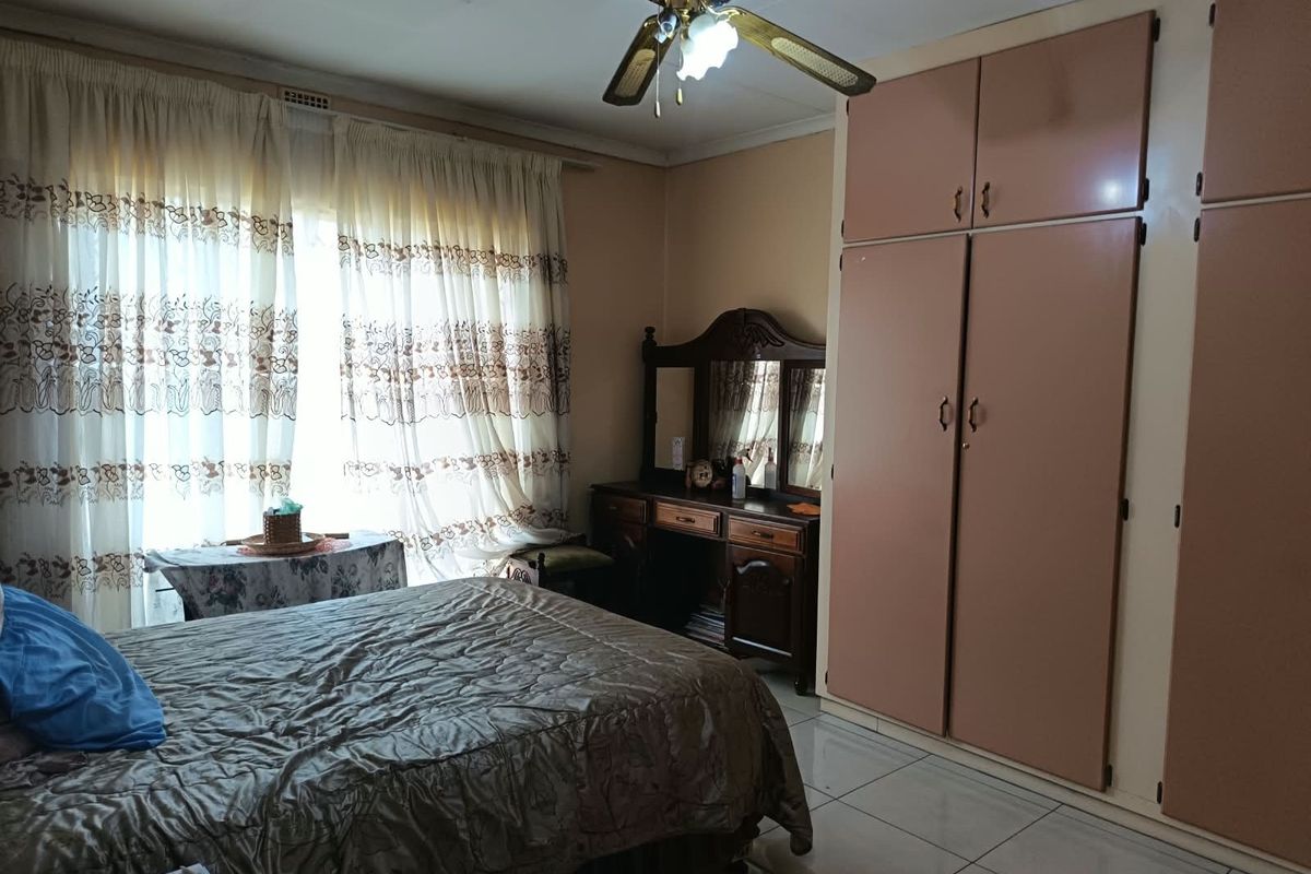 A bedroom featuring built-in cupboards, tiled flooring, and a ceiling fan, offering a functional space with potential for modern updates.