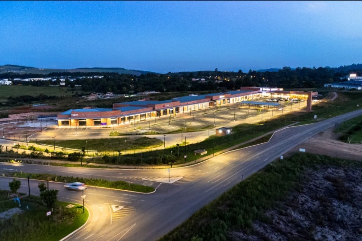 Aerial view of a modern commercial office complex at dusk, featuring extensive parking facilities and direct road access.