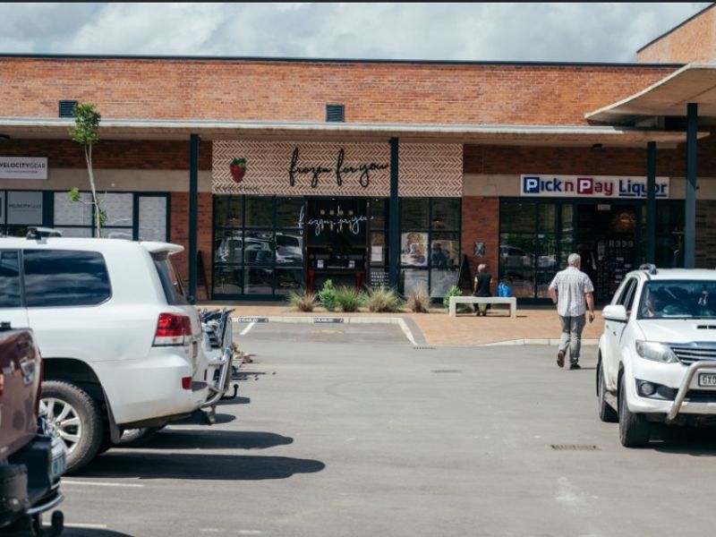 Front exterior view of a commercial office and retail complex featuring a brick facade, covered walkway, and dedicated parking area.