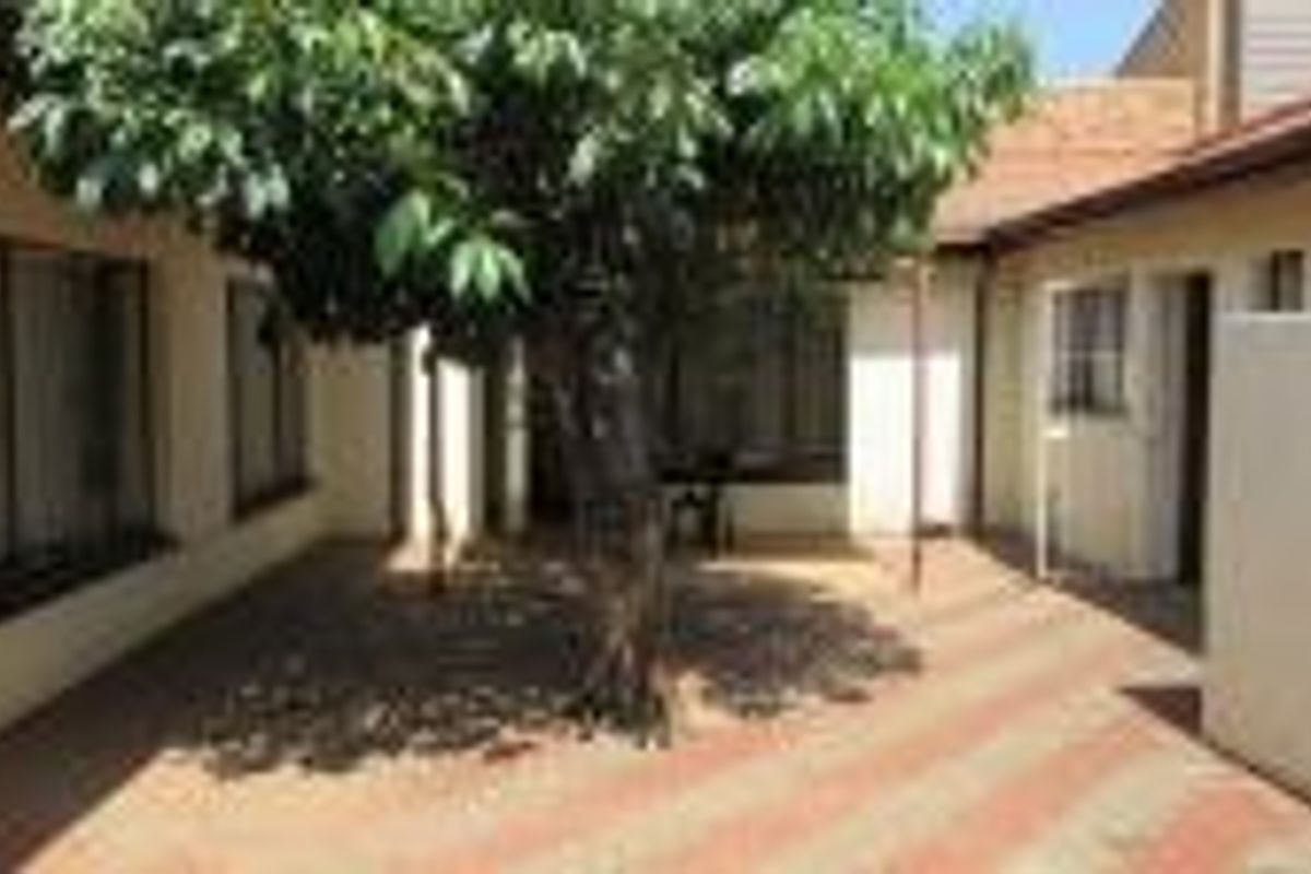 A private rear courtyard featuring paved flooring and a central tree, providing a quiet outdoor space accessible from the main dwelling.
