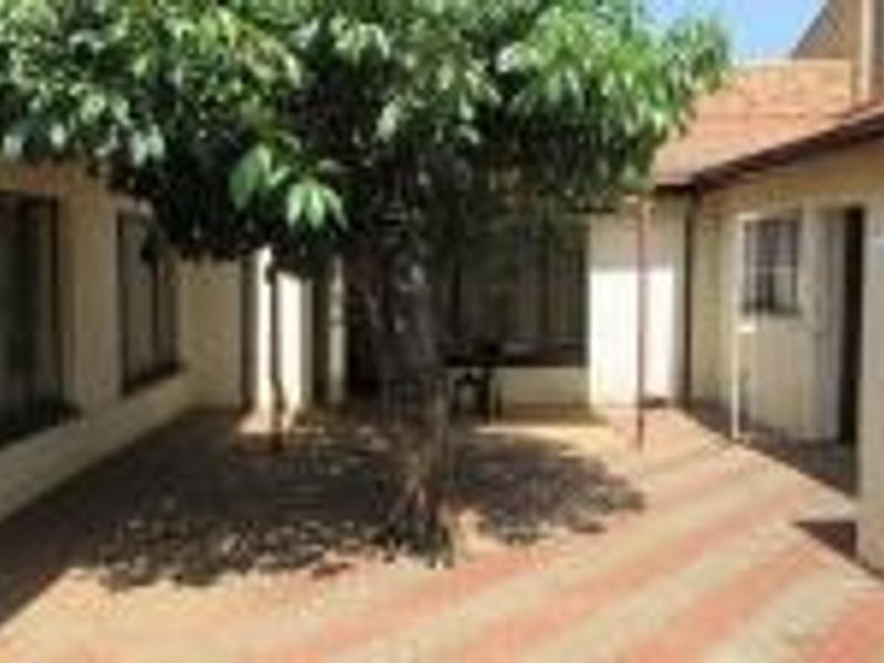 A private rear courtyard featuring paved flooring and a central tree, providing a quiet outdoor space accessible from the main dwelling.
