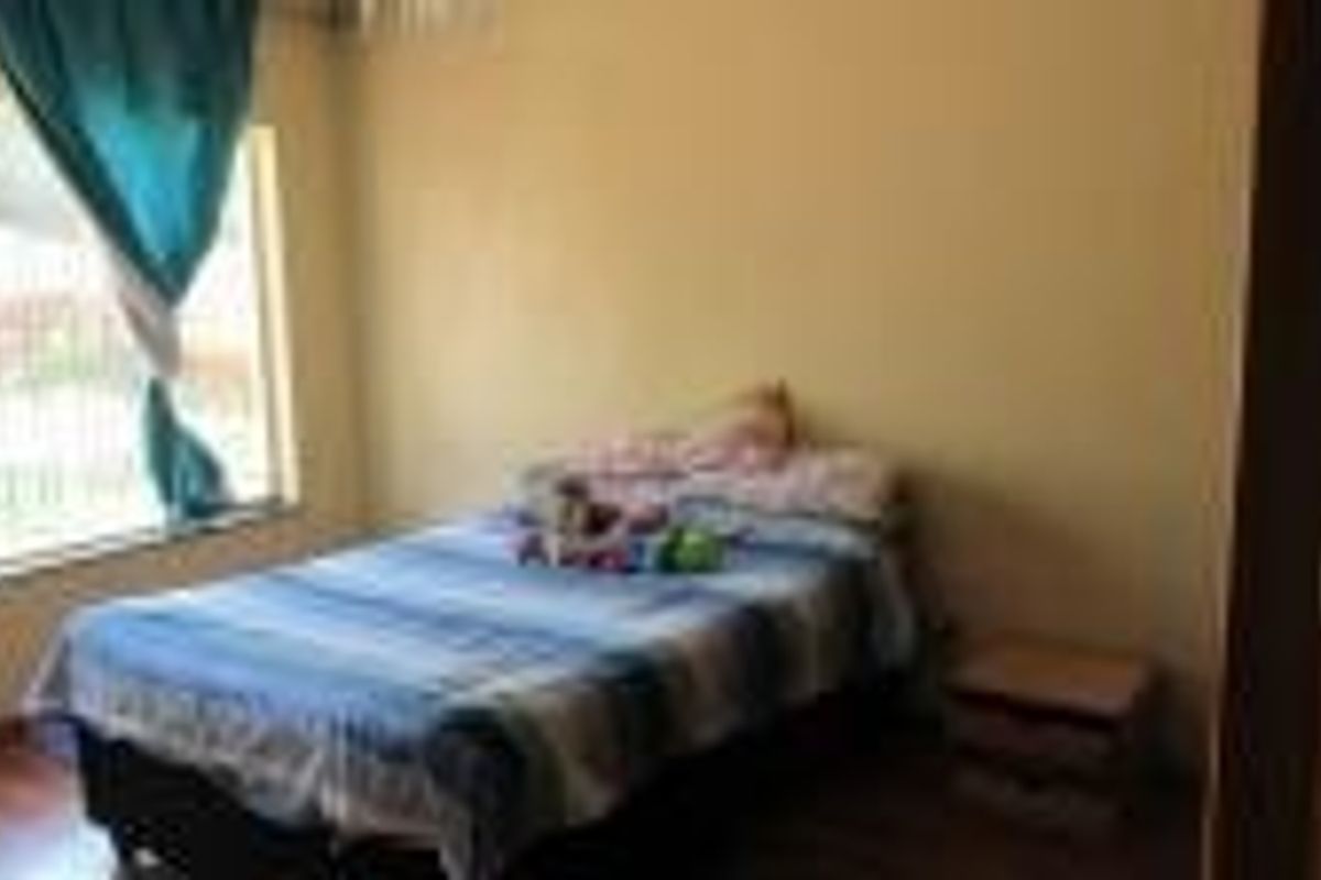 A standard bedroom featuring laminate flooring and a large window, providing natural light to the space.