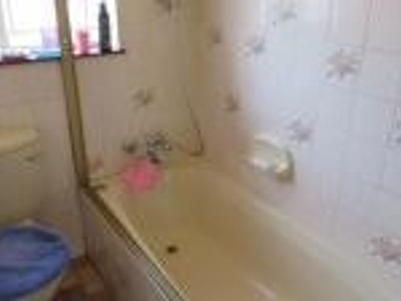 A dated bathroom featuring a standard bathtub, toilet, and patterned wall tiles, offering potential for a modern renovation.