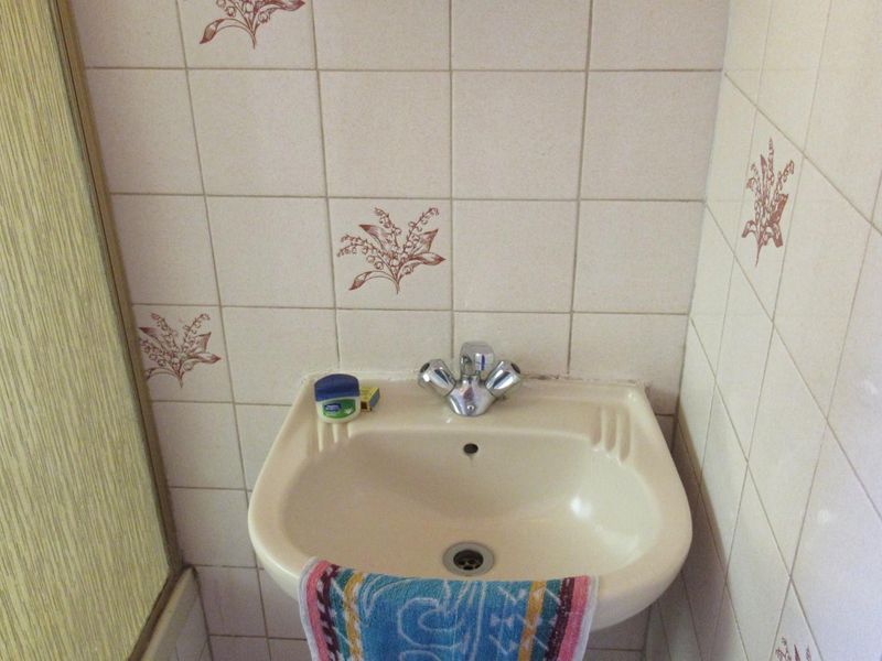 A compact bathroom featuring a wall-mounted basin with a chrome mixer tap and decorative ceramic wall tiling.